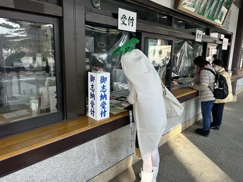 大根の着ぐるみ姿で受付に立つ社員