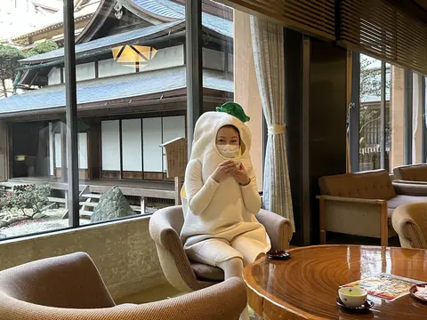 椅子に座ってひと休みする大根の着ぐるみ姿の社員